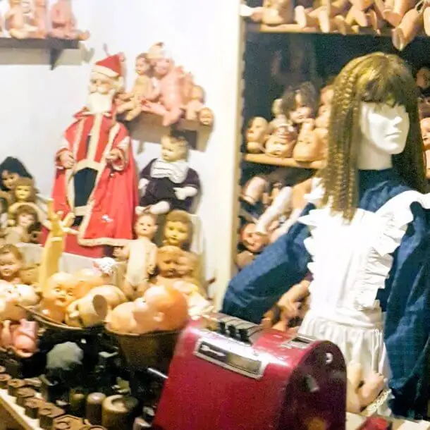 Vintage red cash register counter surrounded by antique dolls at the Hospital de Bonecas Lisbon.