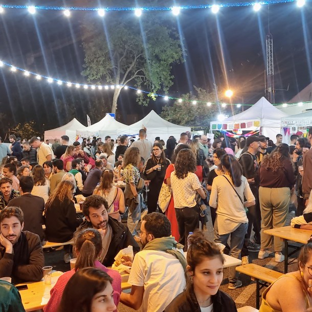Massive street festival crowd dining outdoors at night under string lights during Santo António in Graça Lisbon.