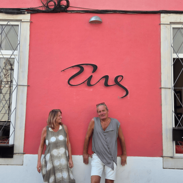 Founders Annette and Thomas standing together in front of the pink wall beneath the Tings logo sign at our relaxed hotel Lisbon house in Graça.