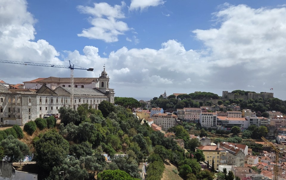 Construction crane over historic convent buildings looking toward Castelo de São Jorge in Lisbon.